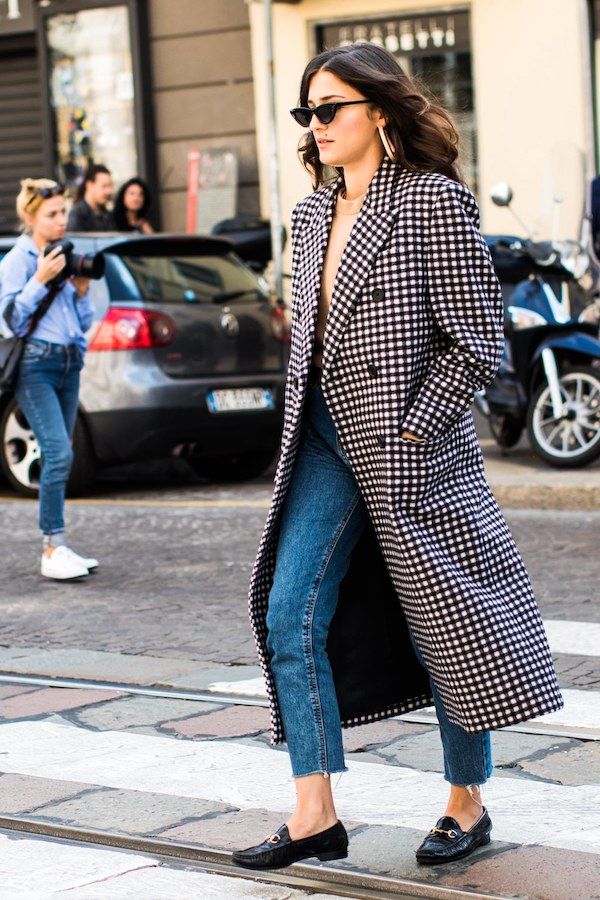 Eleanora Carisi in cat-eye sunglasses, a checkered coat, raw-hem jeans, and loafers